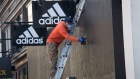 A worker removes screws from wood boarded up on the windows of an Adidas AG store in San Francisco, California, U.S., on Tuesday, June 16, 2020. San Francisco moved into Phase 2B of reopening on Monday, opening up outdoor dining and allowing customers to go inside retail stores to shop.
