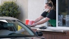 A Starbucks Corp. employee wearing a protective mask and gloves hands a customer an order from a drive-thru window at a store in Hercules, California, U.S., on Tuesday, April 7, 2020.