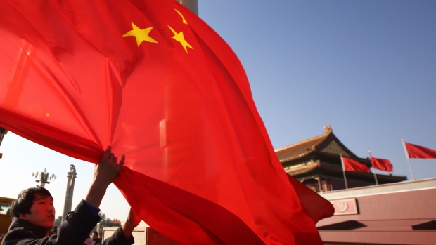 A worker lowers a Chinese national flag in front of Tiananmen Gate in Beijing, China, on Sunday, Nov. 9, 2014. President Xi Jinping signaled China is ready to accept a lower rate of growth, assuring executives that the economy is more resilient than ever and his government can safely guide the country through any slowdown. Photographer: Tomohiro Ohsumi/Bloomberg