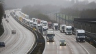 A police car escorts trucks on the M20 motorway in Operation Stack near Ashford, U.K., on Monday, Dec. 21, 2020. Britain's biggest port stopped all traffic heading to Europe, triggering delays to food supplies after the discovery of a new variant of the virus prompted a wave of countries to ban travel from the U.K. Photographer: Chris Ratcliffe/Bloomberg