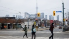 Pedestrians wearing protective masks cross a street in Toronto, Ontario, Canada, on Thursday, Jan. 14, 2021.