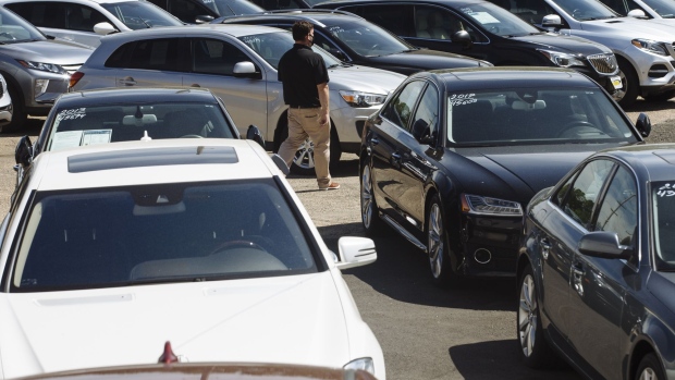 A car dealer walks past cars for sale at a used car dealership in Jersey City, New Jersey, U.S, on Wednesday, May 20, 2020. 