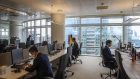 Employees wearing protective face masks sit at alternate desk, as part of social distancing measures, at the Unicredit SpA headquarters in Milan, Italy, on Monday, June 8, 2020. UniCredit SpA will allow essential work trips for many countries starting June 15, as it joins global rivals in cautiously allowing employees to return to pre-pandemic business practices.