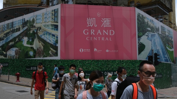 Pedestrians wearing protective masks walk past the Grand Central residential development by Sino Land Co. in Hong Kong, China, on Sunday, May 31, 2020. Home prices in the world's priciest city for real estate have so far held up well amid the economic distress, declining barely more than 1% since January.