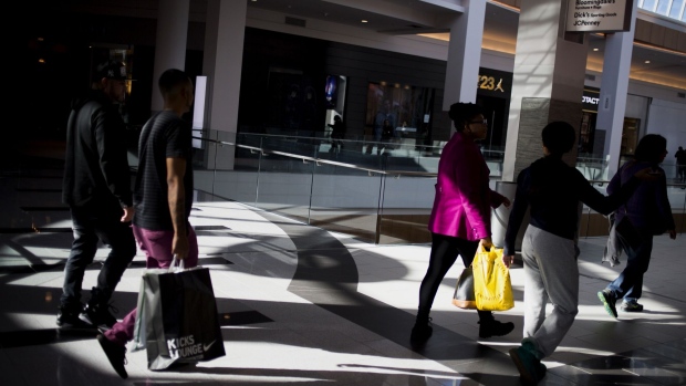 Shoppers carry bags while walking at a mall in Garden City, New York. Photographer: John Taggart/Bloomberg
