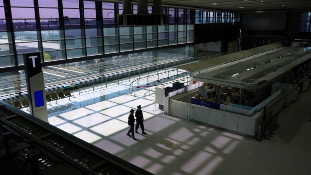 Police officers patrol an empty check-in area in a departure hall at Narita Airport in Narita, Chiba Prefecture, Japan, on Tuesday, Nov. 30, 2021. Japan closed its borders to new foreign arrivals from Tuesday and have its own citizens isolate on arrival from countries where the omicron variant has been found, while experts around the world analyze the risks it presents.