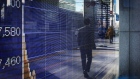 A man walks past a reflected stock chart in this file image. 