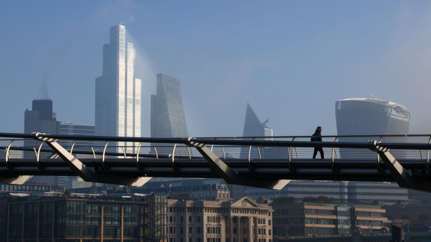 A pedestrian walks across the Millennium Bridge in view of skyscrapers in the City of London, U.K., on Thursday, Nov. 5, 2020. The Bank of England boosted its bond-buying program by a bigger-than-expected 150 billion pounds ($195 billion) in another round of stimulus to help the economy through a second wave of coronavirus restrictions. Photographer: Simon Dawson/Bloomberg