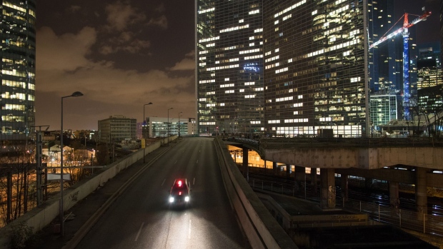 An automobile passes along an overpass as skyscrapers stand illuminated at night in La Defense business district in Paris, France, on Thursday, Feb. 23, 2017. Parisian officials pitching to refugees from Brexit-hit London are appealing to bankers’ hearts as well as their wallets.