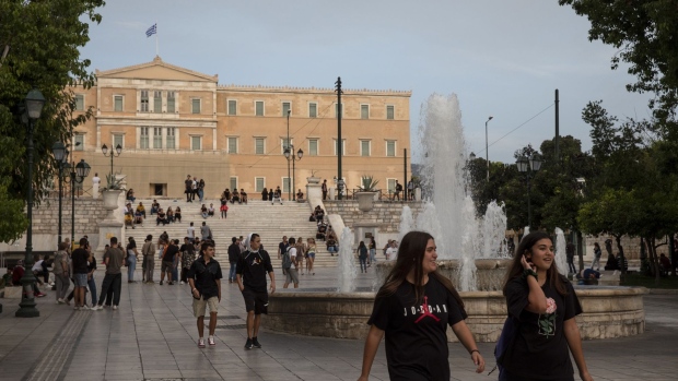 Pedestrians pass the fountain in front of the parliament building in Syntagma square in Athens, Greece, on Sunday, Oct. 4, 2020. Greece predicts the country’s primary deficit will fall to 1% in 2021 from a deficit of 6% in 2020, according to the government’s draft budget for next year. Photographer: Yorgos Karahalis/Bloomberg