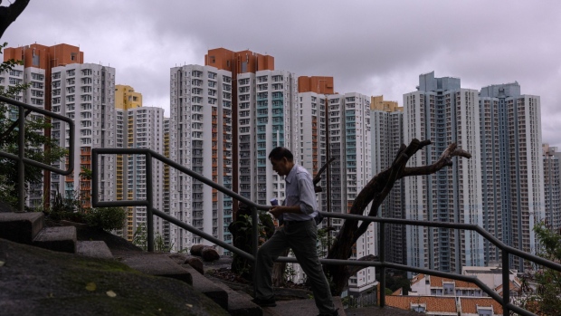 A pedestrian passes residential buildings in Hong Kong, China, on Saturday, June 11, 2022. Hong Kong is preparing to cocoon some 1,000 people involved in the city’s July 1 handover anniversary, fueling speculation that Chinese President Xi Jinping will attend the celebrations. Photographer Louise Delmotte/Bloomberg Photographer: Louise Delmotte/Bloomberg