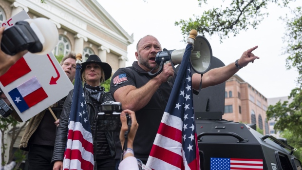 Alex Jones, radio host and creator of the website InfoWars, center, speaks into a megaphone as demonstrators gather during a 'You Can't Close America' rally outside the Texas State Capitol in Austin, Texas, U.S., on Saturday, April 18, 2020. Protesters gathered at the State Capitol Saturday to call for the reopening of the state amid the coronavirus pandemic.