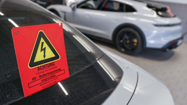 A high voltage warning sign on a Porsche Taycan electric vehicle (EV) during a workshop update at the Porsche SE dealership in Dortmund, Germany, on Wednesday, Sept. 7 2022. Volkswagen AG is pushing ahead with its plan to list a minority stake in the Porsche sports-car maker despite gyrating markets, paving the way for what could be one of Europe's biggest initial public offerings.