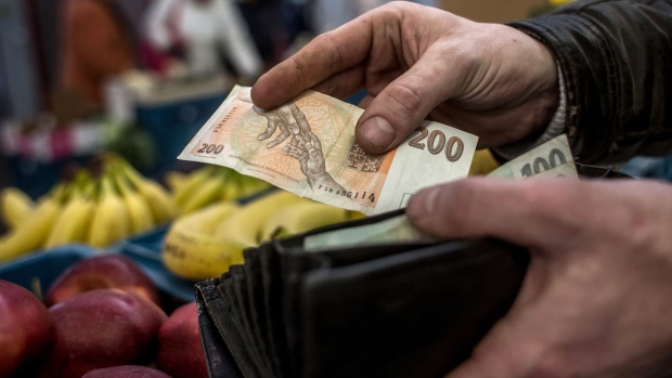 A vendor holds a 200 Czech koruna banknote at a vegetable stall in Holesovicka market hall in central Prague, Czech Republic, on Thursday, Jan. 4, 2017. The Czech Republic posted its biggest ever budget surplus last year after the government spent less than planned and economic growth boosted tax receipts, a rare success that ruling party leaders seized on to stake out their positions before fall elections.