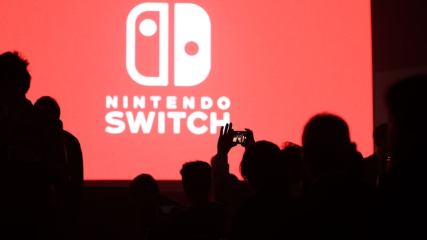 An attendee takes a photograph of the logo for Nintendo Co.'s Switch game console displayed ahead of an unveiling event in Tokyo, Japan, on Friday, Jan. 13, 2017. Nintendo is counting on the Switch to end years of pain at its console division, which released a successor to the popular Wii in 2012 that flopped. Photographer: Kiyoshi Ota/Bloomberg