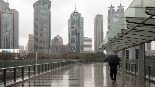 A pedestrian passes buildings in Pudong's Lujiazui Financial District in Shanghai, China, on Monday, Feb. 7, 2022. Asian stocks were mixed amid a rally in China on Monday as the nation’s markets reopened from a holiday, while the prospect of global monetary tightening continued to weigh on bonds. Photographer: Qilai Shen/Bloomberg