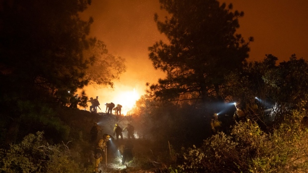 Firefighters saw trees on a hillside in order to open the path for bulldozers during the Mosquito Fire near Foresthill, California, US, on Wednesday, Sept. 7, 2022.