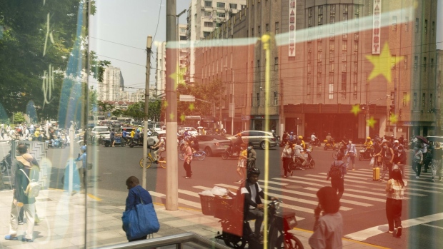 Chinese flags and pedestrians reflected in a window in Shanghai, China, on Friday, June 2, 2023. Chinese stocks staged a sharp rebound as optimism that the Federal Reserve will pause interest-rate hikes in June helped rekindle risk sentiment. Photographer: Raul Ariano/Bloomberg