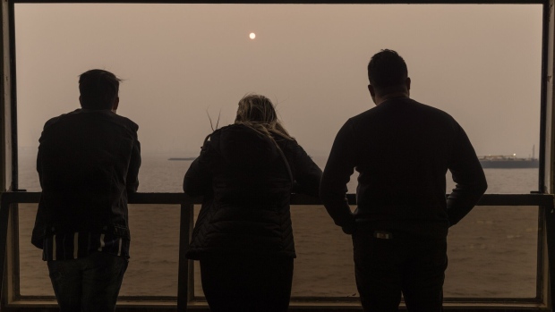 Passengers on the Staten Island Ferry look out over buildings shrouded in smoke from Canada wildfires in New York, on June 7. Photographer: Victor J. Blue/Bloomberg