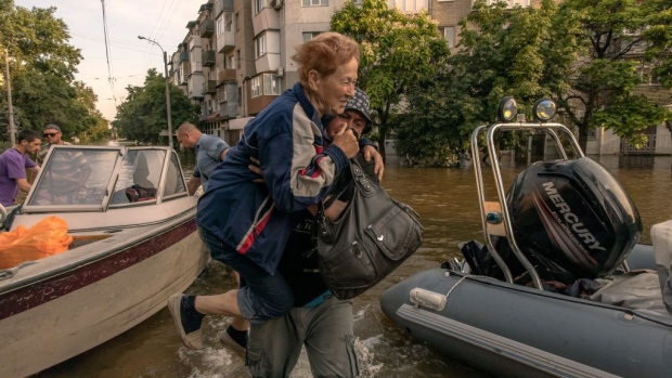KHERSON, UKRAINE - JUNE 09: A man carries an elderly woman who was evacuated from a flooded area on June 9, 2023 in Kherson, Ukraine. Early Tuesday, the Kakhovka dam and hydroelectric power plant, which sit on the Dnipro river in the southern Kherson region, were destroyed, forcing downstream communities to evacuate due to the risk of flooding. The cause of the dam's collapse is not yet confirmed, with Russia and Ukraine accusing each other of its destruction. The Dnipro river has served as a frontline between the warring armies following Russia's retreat from Kherson and surrounding areas last autumn. The dam and plant had been under the control of Russia, which occupies a swath of land south and southeast of the river. (Photo by Roman Pilipey/Getty Images)