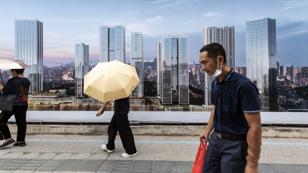 Pedestrians pass an advertisement for residential buildings in Shenzhen, China, on Wednesday, Aug. 9, 2023. China's economic recovery is being weighed down by a worsening property slump, with the latest data likely to show little sign of a rebound in growth. Photographer: Qilai Shen/Bloomberg