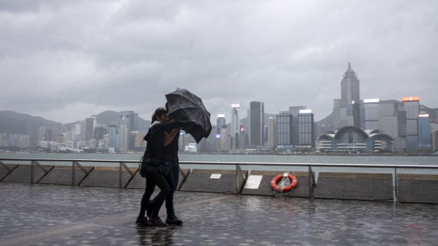 Pedestrians brace from the wind and rain on the waterfront in Tsim Sha Tsui district during a No. 8 storm signal raised for Super Typhoon Saola in Hong Kong, China, on Friday, Sept. 1, 2023.  Photographer: Justin Chin/Bloomberg