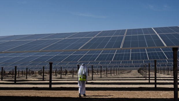 An employee walks between solar panels at the Dhafra solar power plant near Abu Dhabi, United Arab Emirates, on Monday, Nov. 13, 2023. In June, Masdar and Taqa, the Abu Dhabi National Energy Co., began commercial operations at the 2-gigawatt Dhafra solar plant, developed with partners Jinko Power Co. and Electricite de France SA’s renewables arm and formally inaugurated it on Thursday. Photographer: Natalie Naccache/Bloomberg