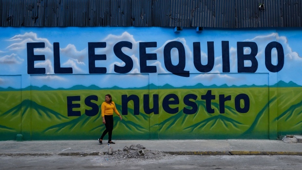 A pedestrian walks past a mural that reads "The Essequibo Is Ours," during a referendum vote in Caracas, Venezuela, on Sunday, Dec. 3, 2023. Following massive offshore oil discoveries in the region by Exxon Mobil Corp. and others, and with elections approaching, President Maduro is inflaming regional tension by reviving a long-dormant border dispute over the area known as the Essequibo.