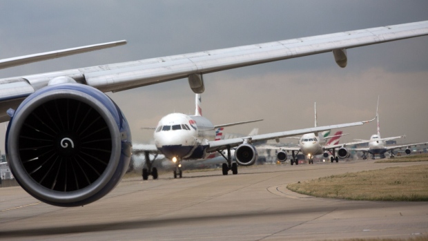 A row of passenger aircraft line up ahead of take off from London Heathrow airport in London, U.K., on Friday, Oct. 7, 2016. Europe's busiest hub is stepping up its pitch for a new runway with a much-delayed U.K. government decision on where to locate additional flight capacity for southern England likely to announced in the coming weeks. Photographer: Simon Dawson/Bloomberg
