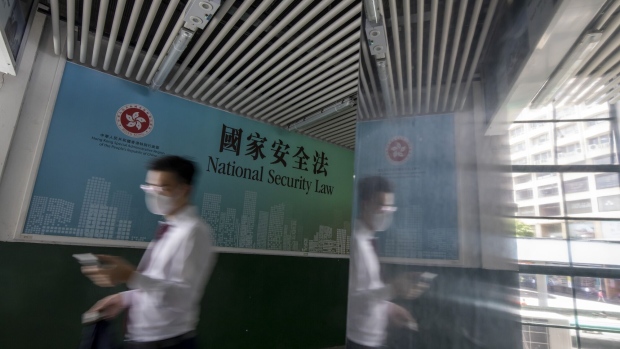 A pedestrian wearing a protective mask walks past a government-sponsored advertisement promoting a new national security law in Hong Kong, China, on Monday, June 29, 2020. The national security law that China could impose on Hong Kong as early as this week won't need to be used if the financial hub's residents avoid crossing certain "red lines," according to Bernard Chan, a top adviser to Hong Kong Chief Executive Carrie Lam.