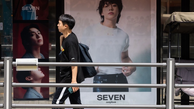A pedestrian in front of a photograph of JungKook, a member of K-pop boy band BTS, near the Hybe Co. headquarters in Seoul, South Korea.