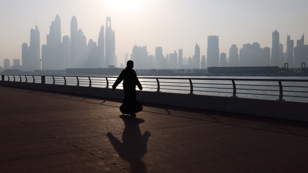 A visitor walks along the corniche, backdropped by skyscrapers on the city skyline, in Dubai, United Arab Emirates, on Wednesday, Nov. 29, 2023. More than 70,000 politicians, diplomats, campaigners, financiers and business leaders will fly to Dubai to talk about arresting the world’s slide toward environmental catastrophe. Photographer: Hollie Adams/Bloomberg