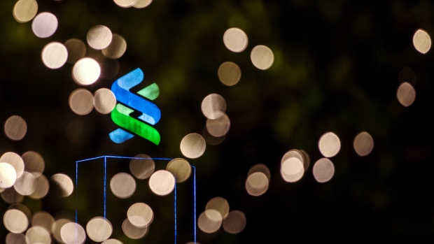 Signage is illuminated atop the Standard Chartered Bank building at night in Hong Kong, China, on Thursday, July 25, 2019. Standard Chartered is scheduled to release interim earnings results on Aug. 1. Photographer: Paul Yeung/Bloomberg