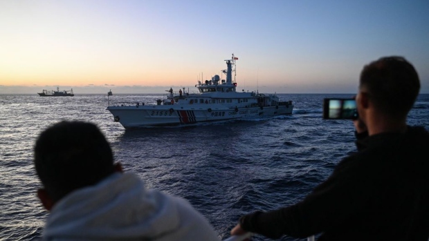 Philippine Coast Guard personnel filming a China Coast Guard vessel during a supply mission in the disputed South China Sea. Photographer: Jam Sta Rosa/AFP/Getty Images