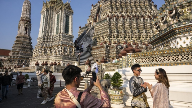 Tourists in Thai traditional dress pose for photographs at Wat Arun Ratchawararam Rathawaramahawihan in Bangkok.