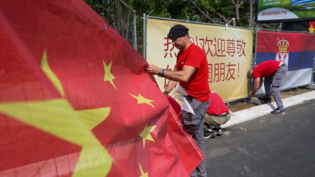 A worker attaches a large national flag of China to fencing ahead of the state visit of China's President Xi Jinping, in Belgrade, Serbia, on Tuesday, May 7, 2024.  Photographer: Oliver Bunic/Bloomberg 