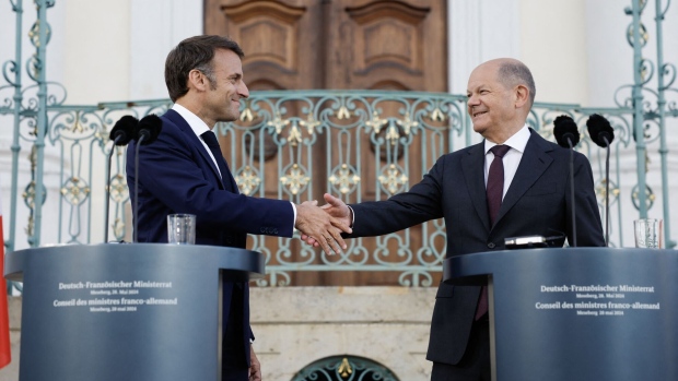 Emmanuel Macron and Olaf Scholz shake hands after their joint press conference at Schloss Meseberg Palace in Meseberg, Germany on May 28. Photographer: Odd Andersen/AFP/Getty Images