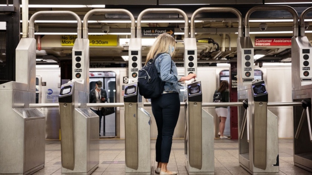 A commuter swipes a metro card through a turnstile slot at a subway station in New York. Photographer: Sarah Blesener/Bloomberg