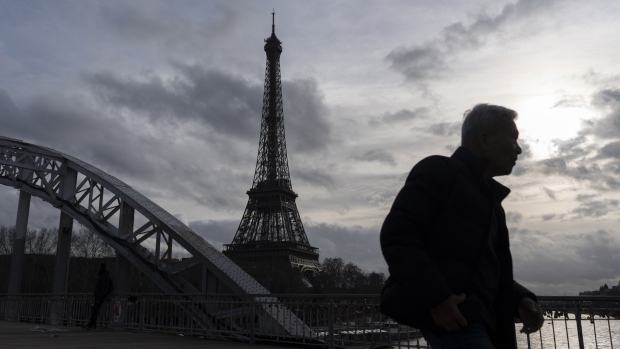 A pedestrian crosses a footbridge over the River Seine, in view of the Eiffel Tower in central Paris, France, on Wednesday, Feb. 14, 2024. Olympic organizers began working with Paris officials three years ago to clean the Seine, a venue for Paris 2024 Olympic swimming events. Photographer: Nathan Laine/Bloomberg