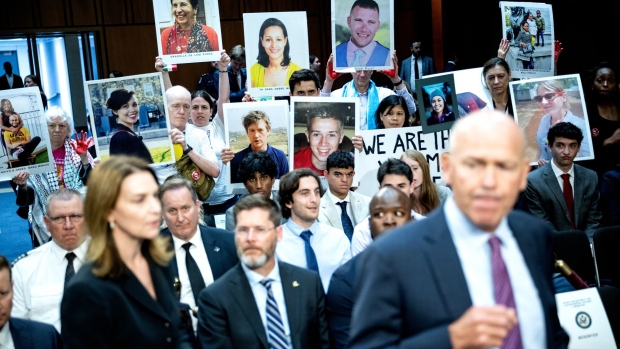 <p>Relatives of Boeing airplane crash victims hold images as Boeing’s Dave Calhoun arrives at a hearing in Washington, DC, on June 18.</p>