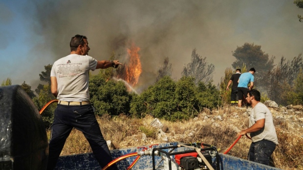 <p>Volunteers work to extinguish a wildfire near Stamata, northeast of Athens, Greece, on June 30.</p>