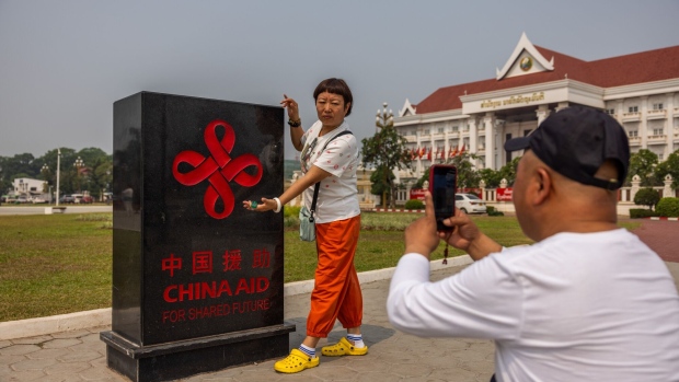 <p>Tourists pose for photos with a China Aid plaque at the Patuxay Victory Monument in Vientiane.</p>