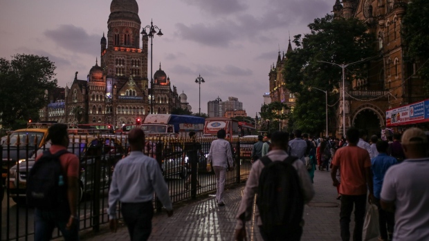 Pedestrians walk towards the Chhatrapati Shivaji Terminus (CST) train station at dusk in Mumbai, India, on Wednesday, Oct. 4, 2023. India’s central bank added more firepower to its inflation-busting toolkit as the nation’s entry into global bond index is set to test policymakers’ resolve to manage billions of dollars of inflows that could further fan price pressures. Photographer: Dhiraj Singh/Bloomberg